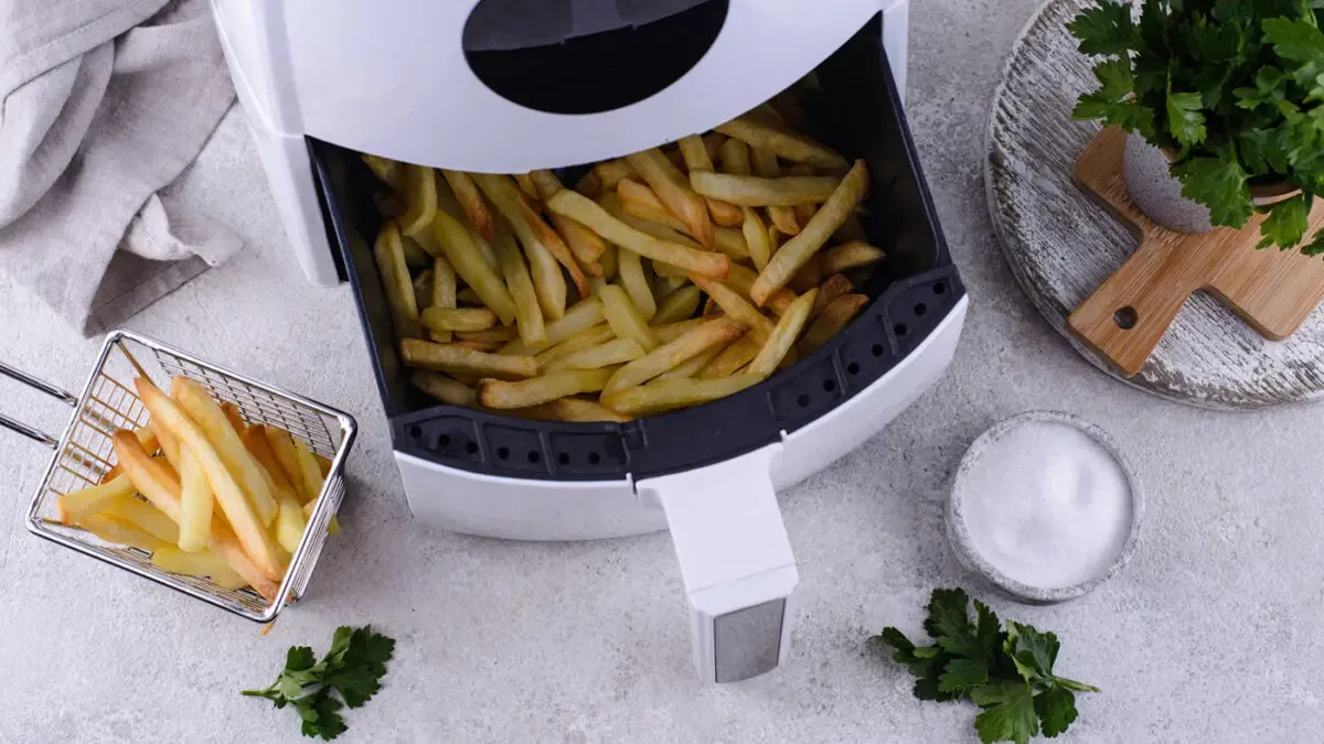 Vue de dessus d'une friteuse sans huile blanche ouverte sur des frites maison