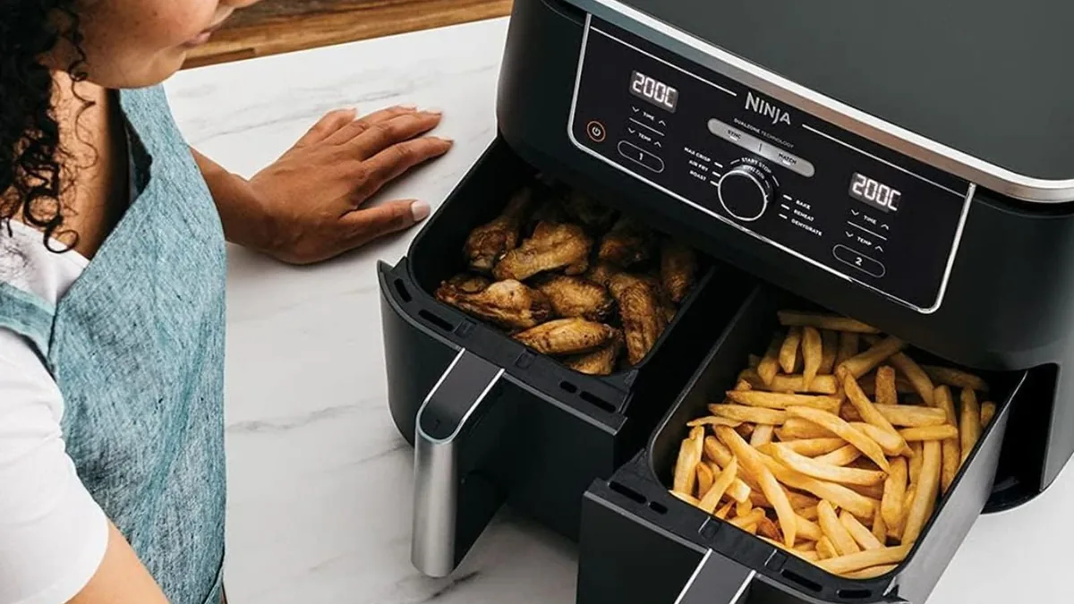 Friteuse à deux tiroirs indépendants, ailes de poulet dorées dans le panier gauche et frites dans le panier droit