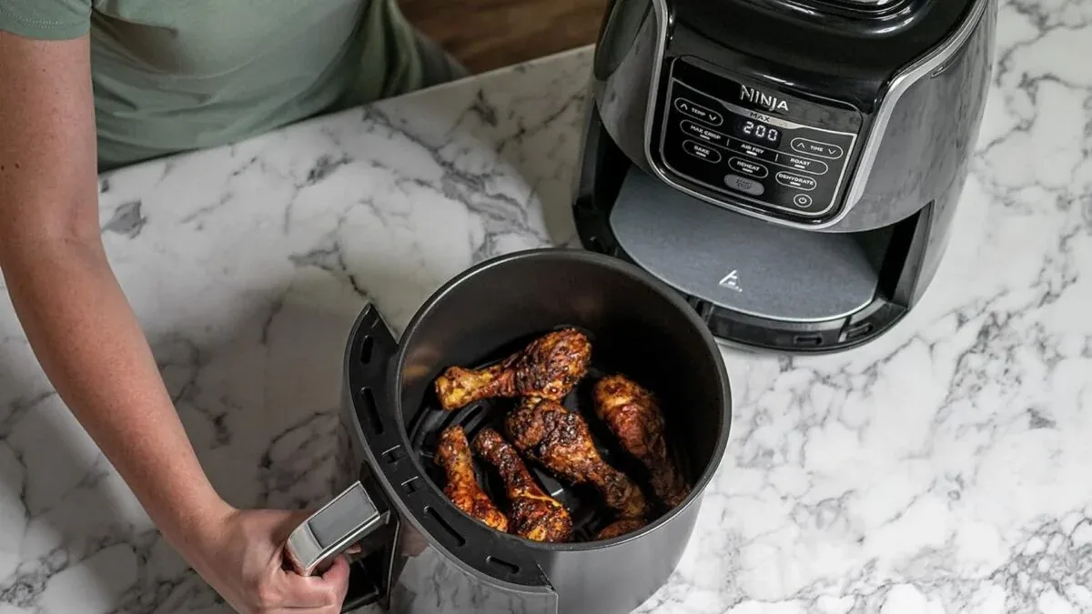 Panier de friteuse sans huile rempli de pilons de poulet dorés et rôtis