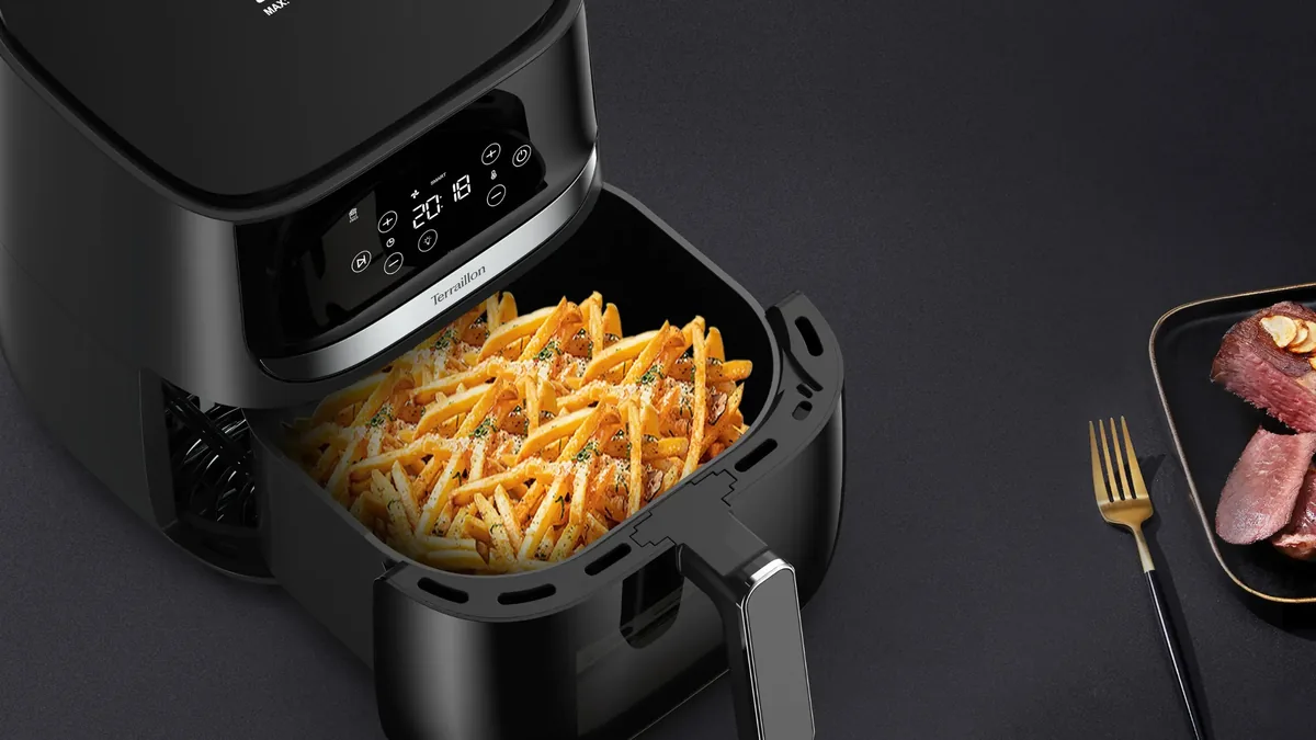 Tiroir de friteuse sans huile rempli de frites assaisonnées au parmesan et au persil