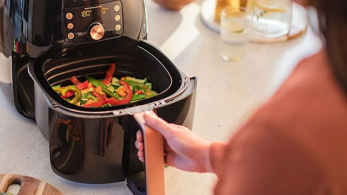 Tiroir de friteuse sans huile avec des poivrons et des courgettes en cours de cuisson